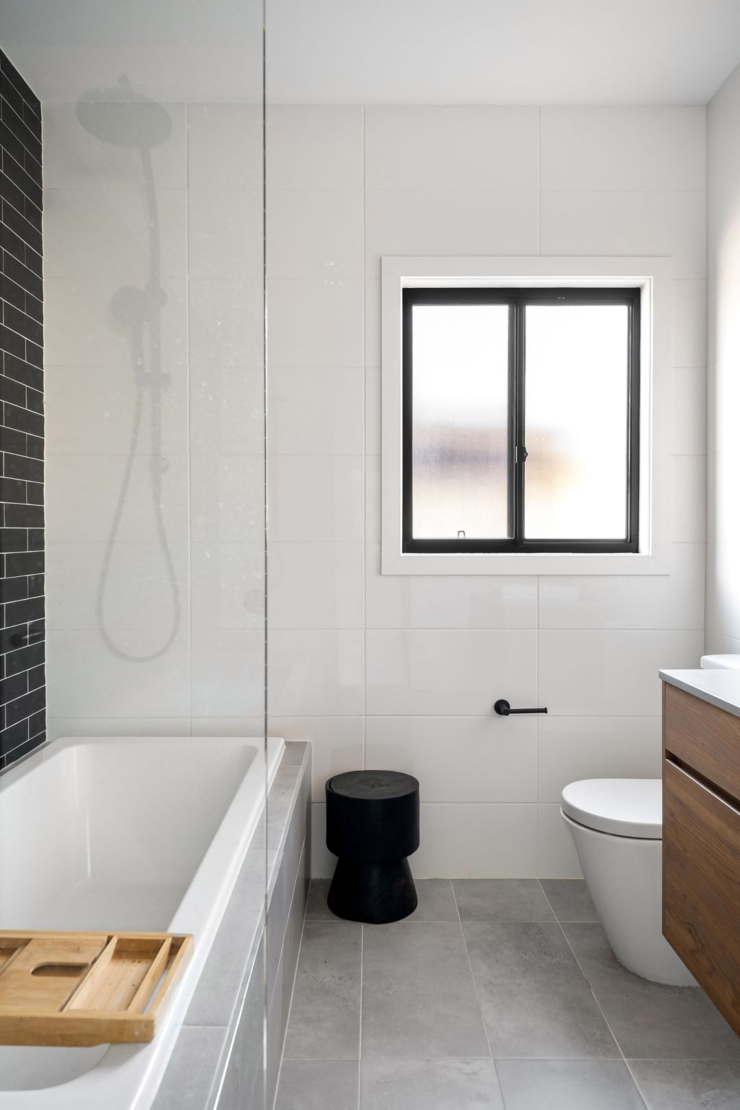 Ein fertiges helles Bad mit Badewanne, Fenster und bodentiefer Dusche hinter Glas