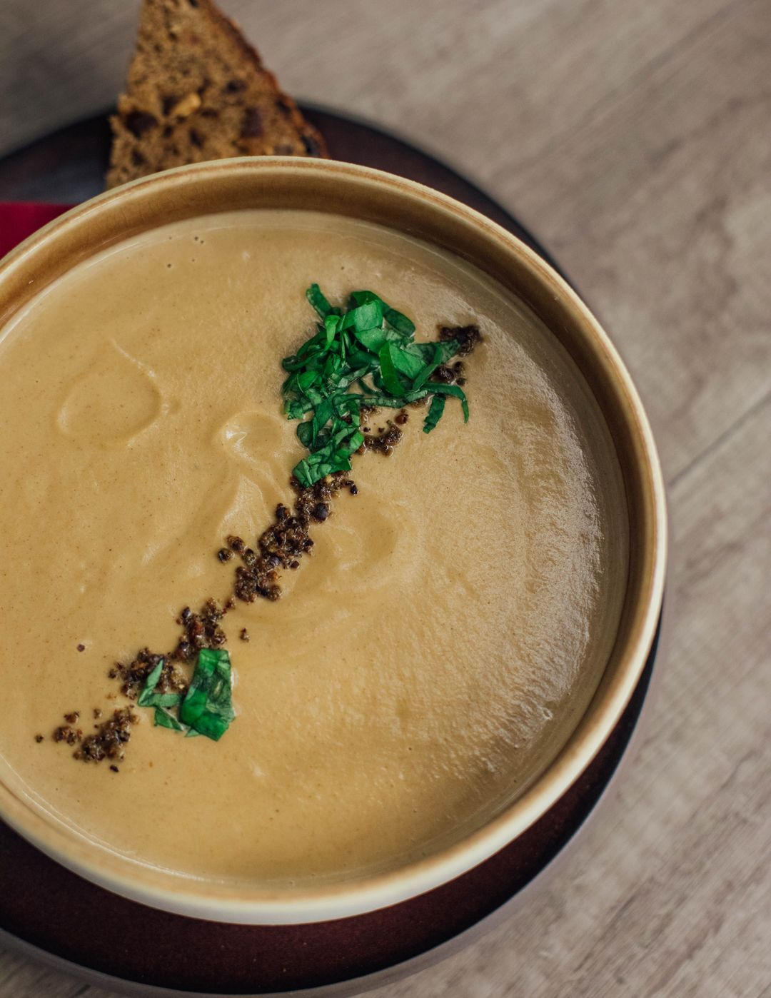 Eine helle Cremesuppe mit einem Streifen Kräuter in einer Schale