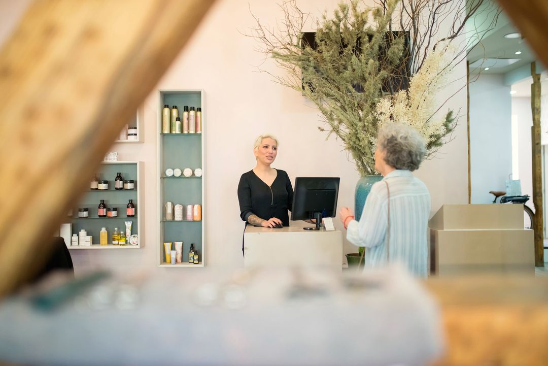 Empfang des Salons mit hellem Tresen, Regalen und einer Vase mit Trockenblumen