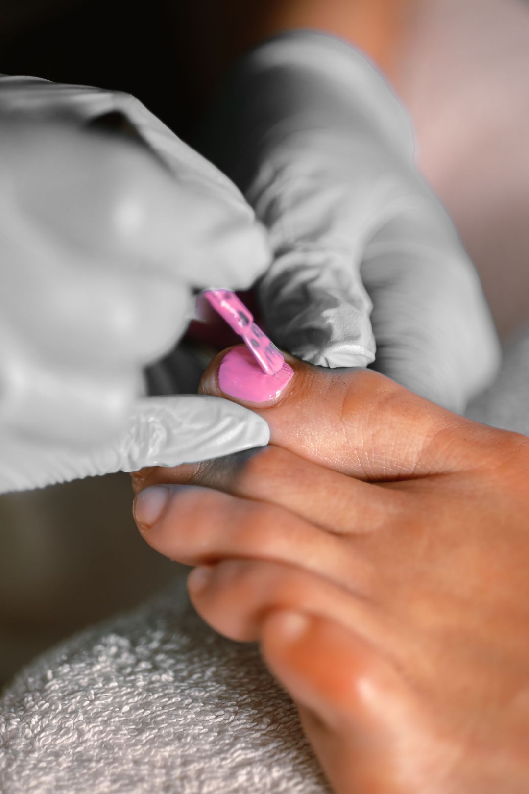 Bei einer Pediküre wird rosa Lack auf einen Zehennagel gestrichen